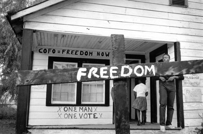 After the Ku Klux Klan burned this cross in front of a Mississippi Delta Freedom House, a civil rights worker transformed it with a painted message.  Tamio Wakayama  Indianola, Mississippi, 1964 