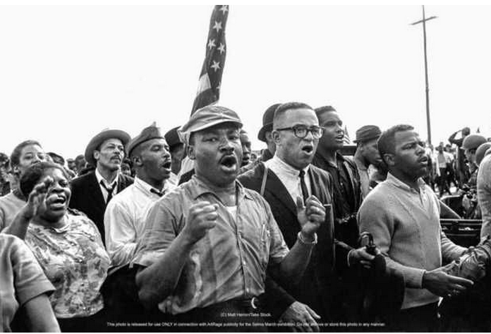 Matt Herron photograph of the Rev.Martin Luther King Jr. leading singing marchers from Selma to Montgomery
